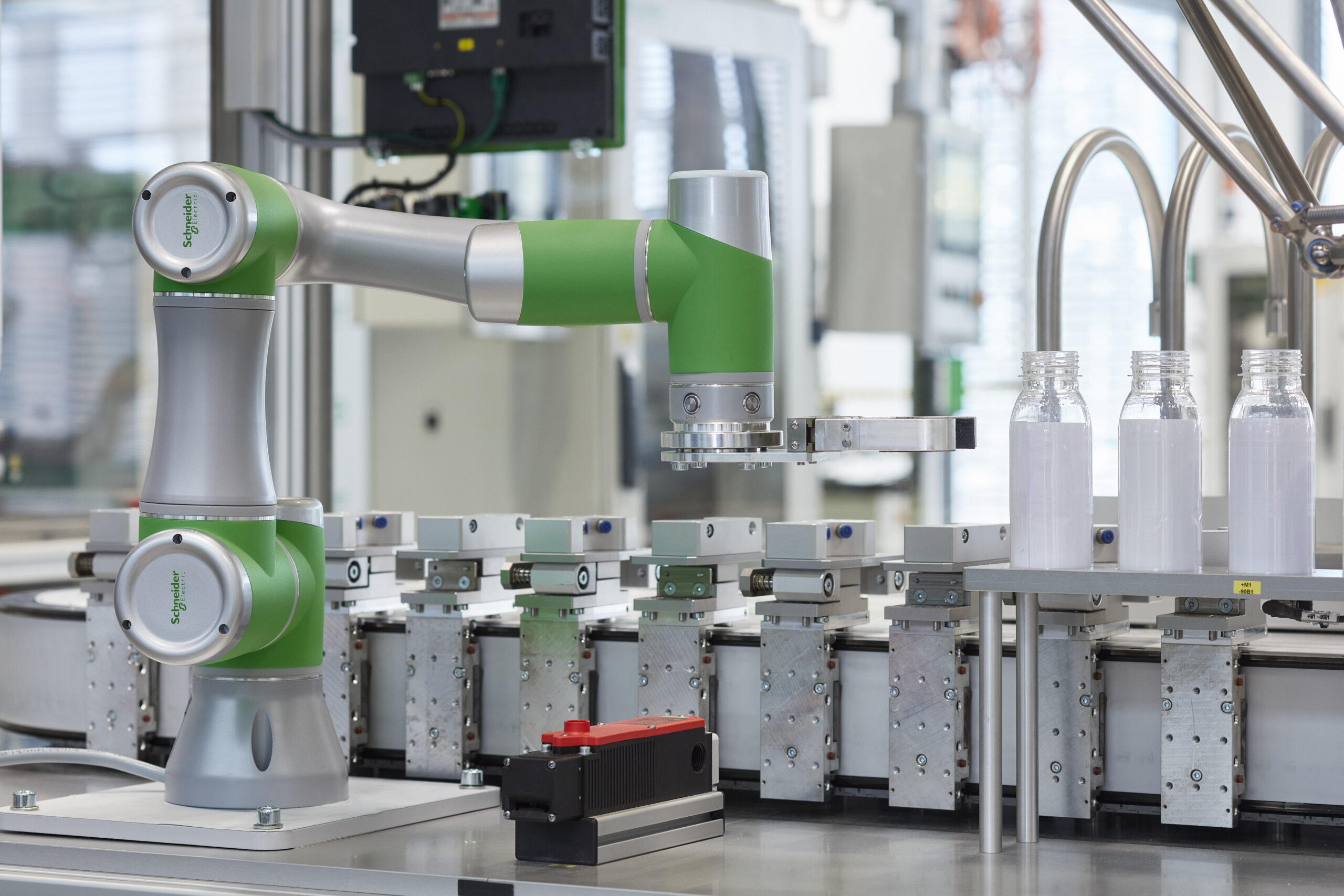 A robotic arm assists with packaging of bottles in a manufacturing facility.